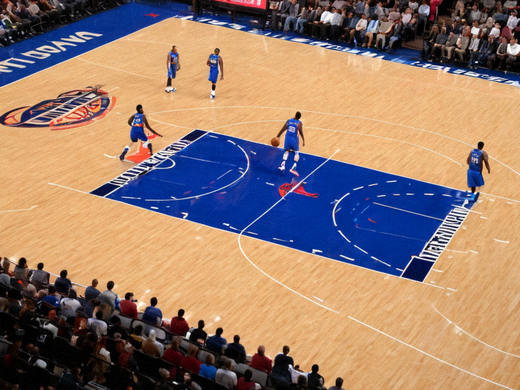 NBA常规赛现场，球员突破上篮瞬间，场边记分牌与观众席清晰可见
